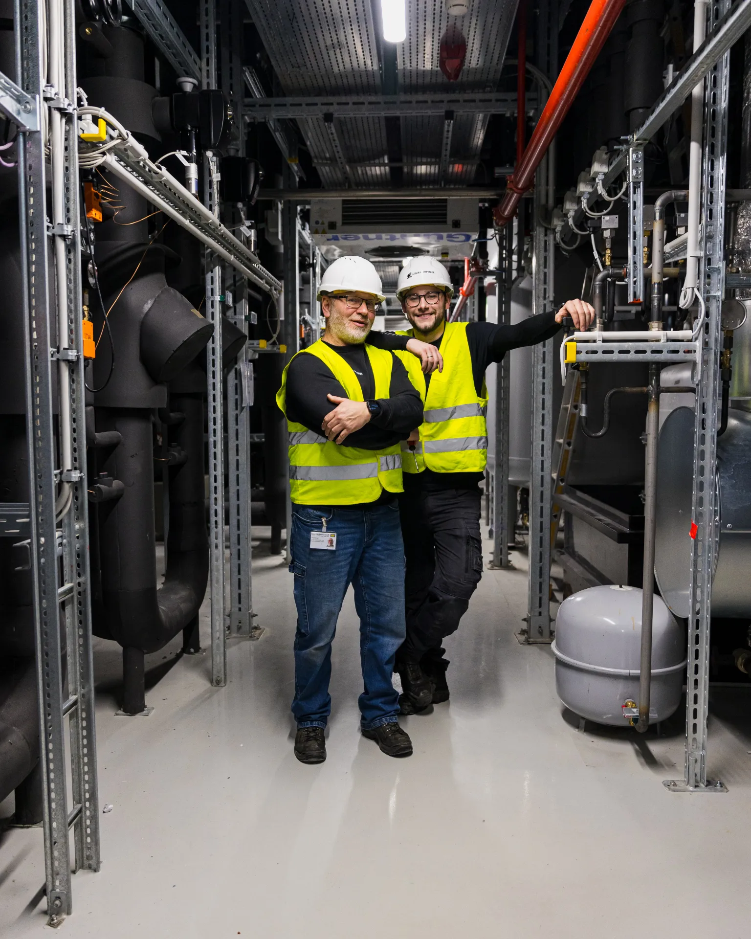 Zwei LEGER-Servicetechniker mit Helm in einer Technikzentrale